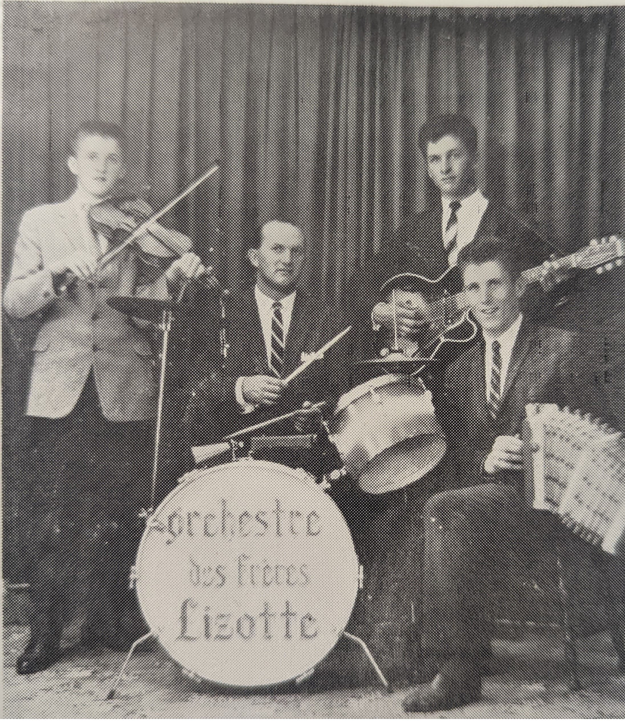 Photographie en noir et blanc de l’orchestre des Frères Lizotte. De gauche à droite, ne veston et cravate : Jean-Paul Lizotte, Jean-Léon Pelletier, Maurice Lizotte et Réjean Lizotte. Certains sont assis et d’autres sont debout devant un rideau.