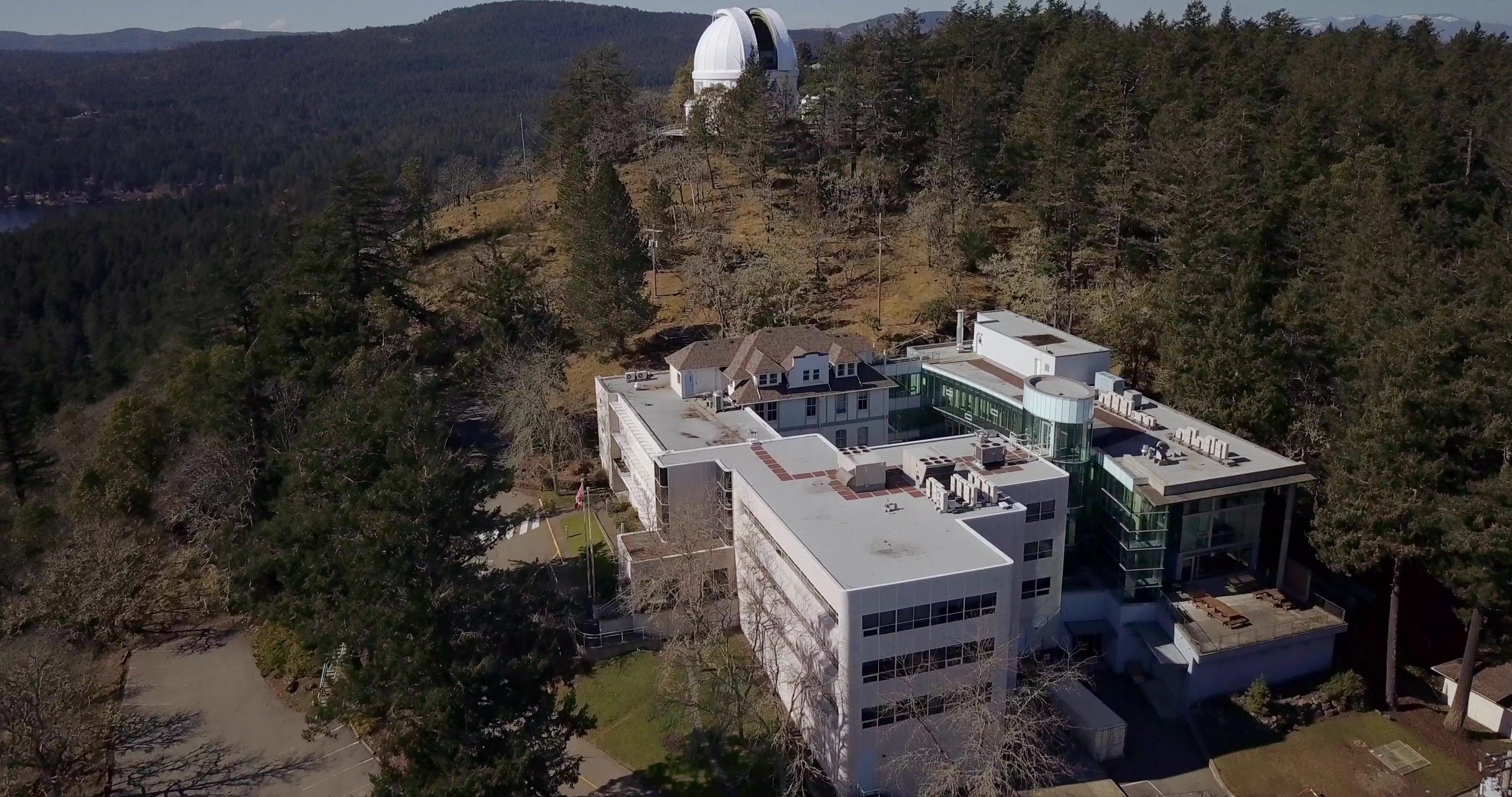 Photo prise par un drone d’un très grand bâtiment situé à flanc de colline. Au sommet de la colline se trouve une coupole de télescope blanche.