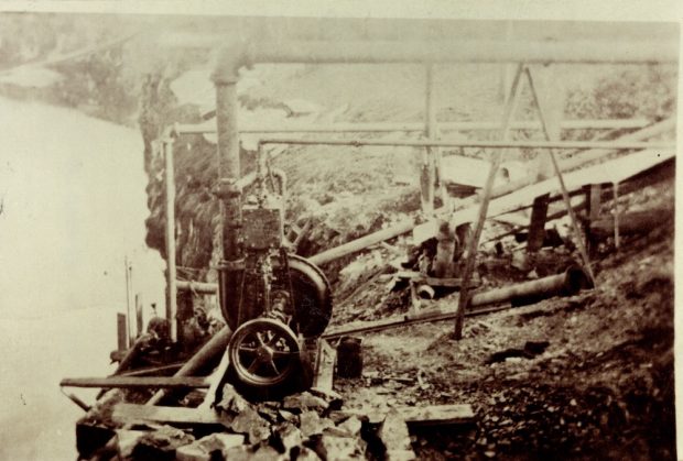  Une photographie en noir et blanc d’une pompe à eau avec des tuyaux fixés au bord d’une carrière