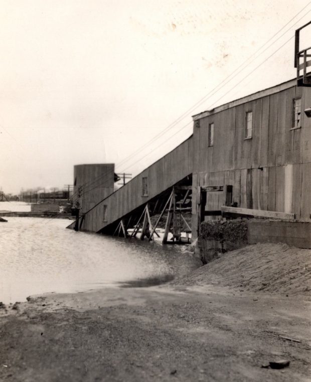 Photographie en noir et blanc d’un bâtiment de carrière partiellement immergé dans l’eau