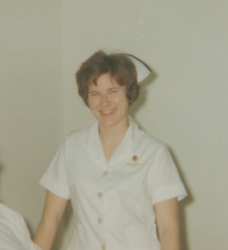 Photographie en couleur d'une femme souriante en uniforme d'infirmière.