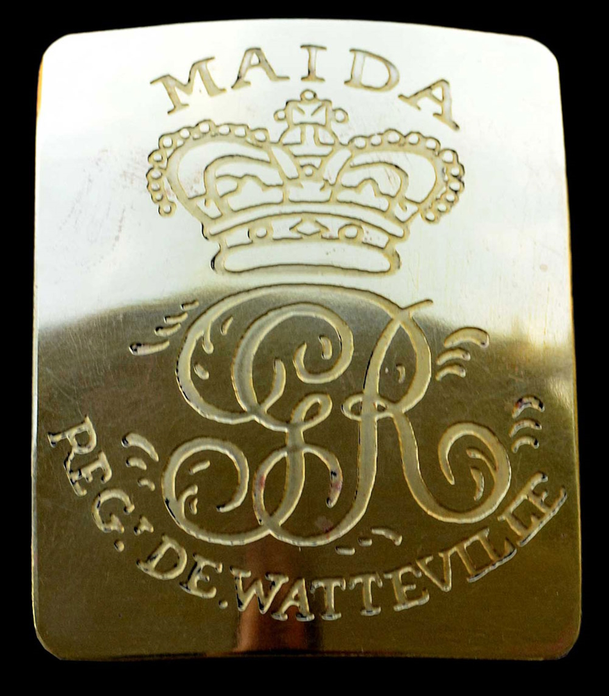 Plaque de ceinture dorée et rectangulaire portant les lettres GR et le mot « Maida ».