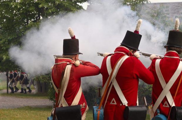 Trois soldats en veste rouge tirent sur un groupe de soldats américains