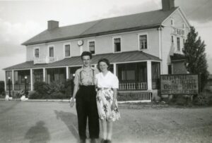 Photo en noir et blanc d'un couple devant un hôtel.