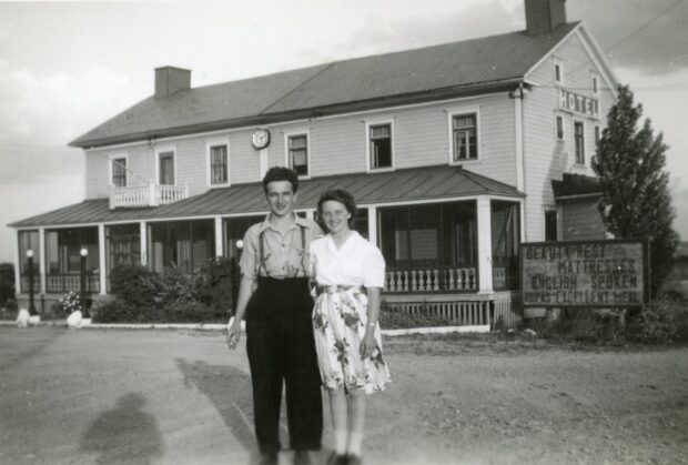 Photo en noir et blanc d'un couple devant un hôtel.