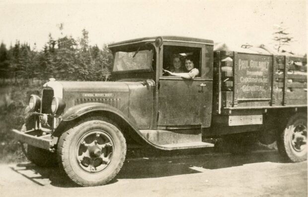 Photo en noir et blanc de deux femmes au volant d'un camion ancien.