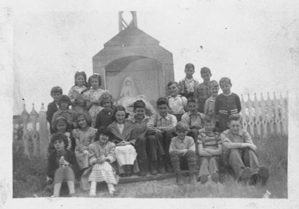 Photo en noir et blanc d'un groupe d'enfants assis dehors. 