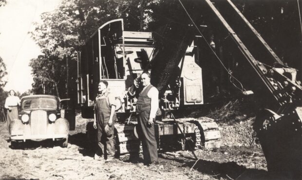 Photo en noir et blanc de deux hommes devant la machinerie.