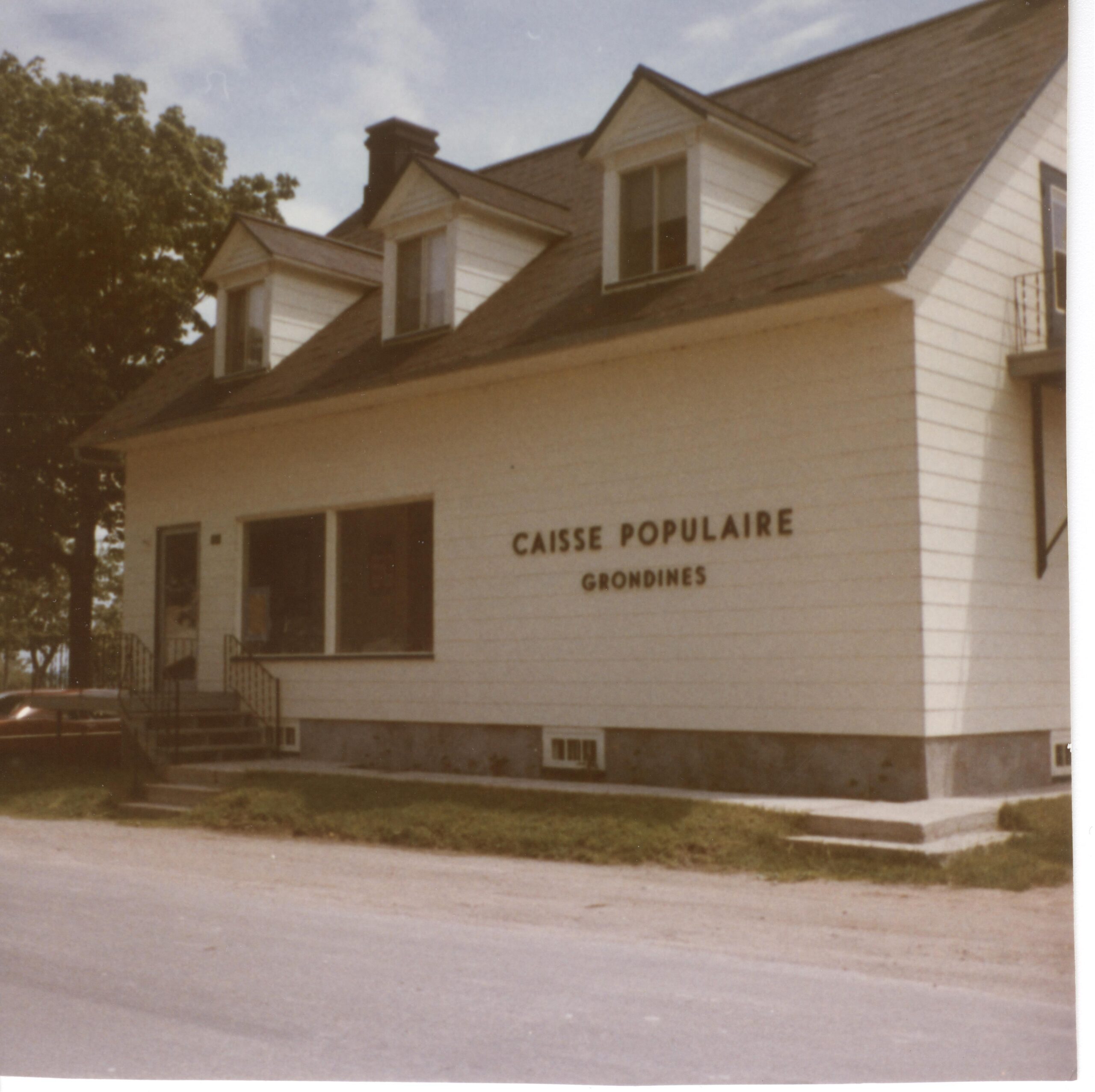 Petite maison blanche sur laquelle il est inscrit "Caisse populaire - Grondines".