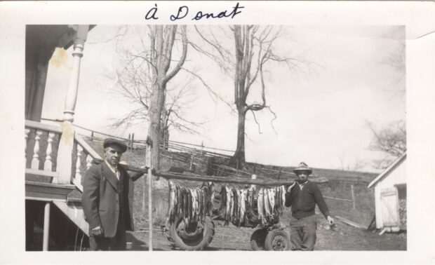 Photo en noir et blanc de deux hommes avec leurs prises de pêche. 