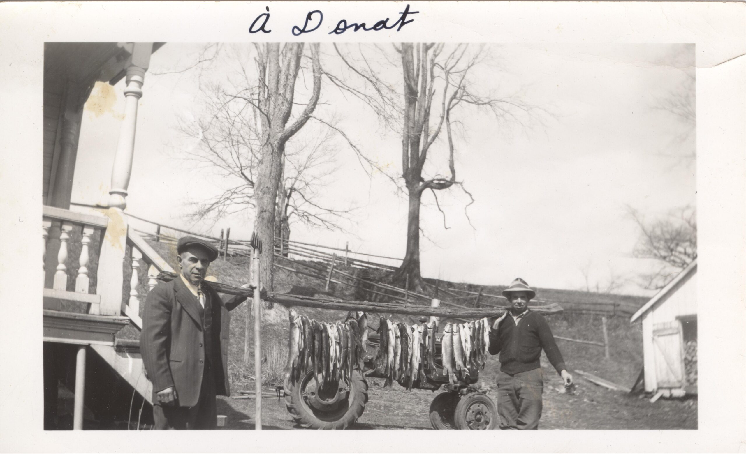 Photo en noir et blanc de deux hommes avec leurs prises de pêche. 