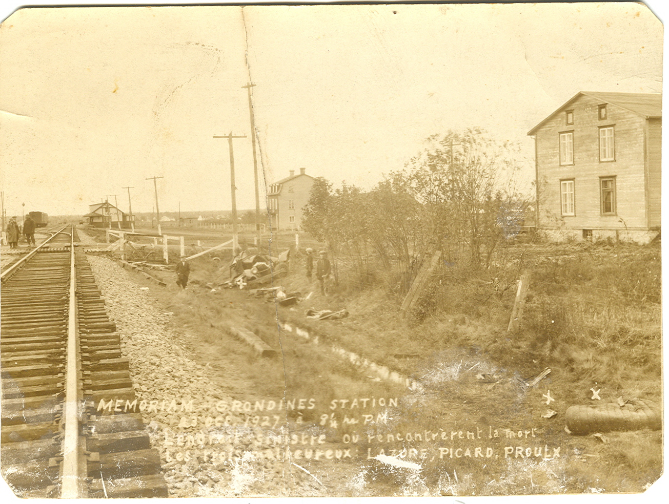 Photo ancienne d'un accident de voiture sur la voie ferrée. Sur la droite, une maison deux étages, au centre un hôtel de trois étages et au loin la gare de train.