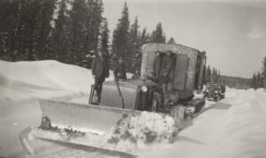 Photo en noir et blanc de six hommes sur une déneigeuse.