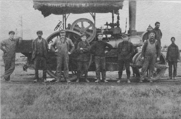 Photo en noir et blanc de neuf hommes devant un rouleau de macadam.