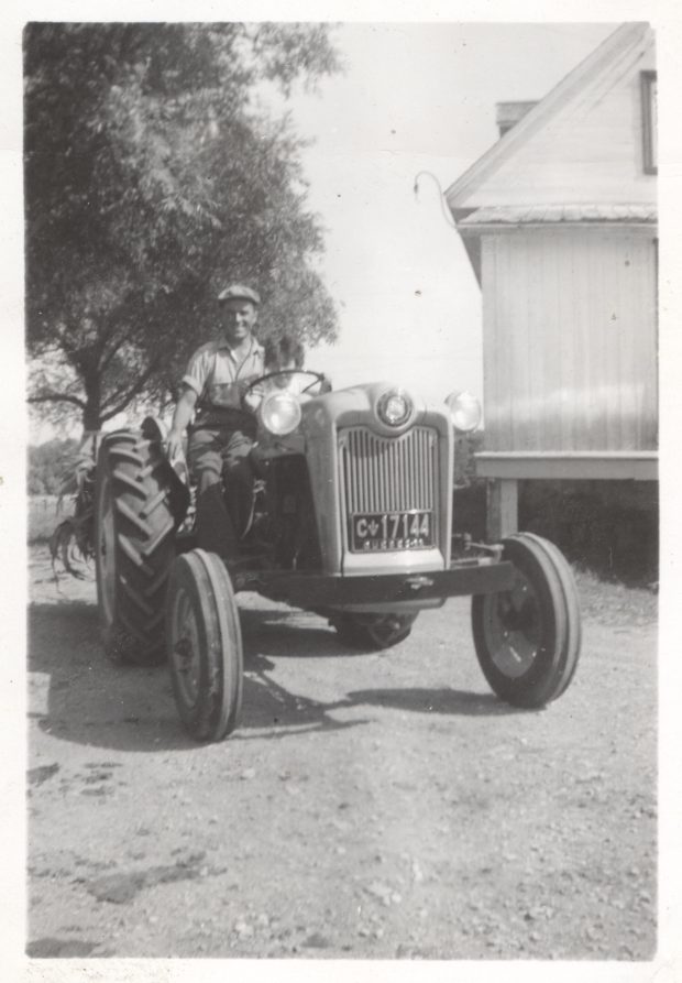 Photo en noir et blanc d'un homme assis sur un tracteur. 