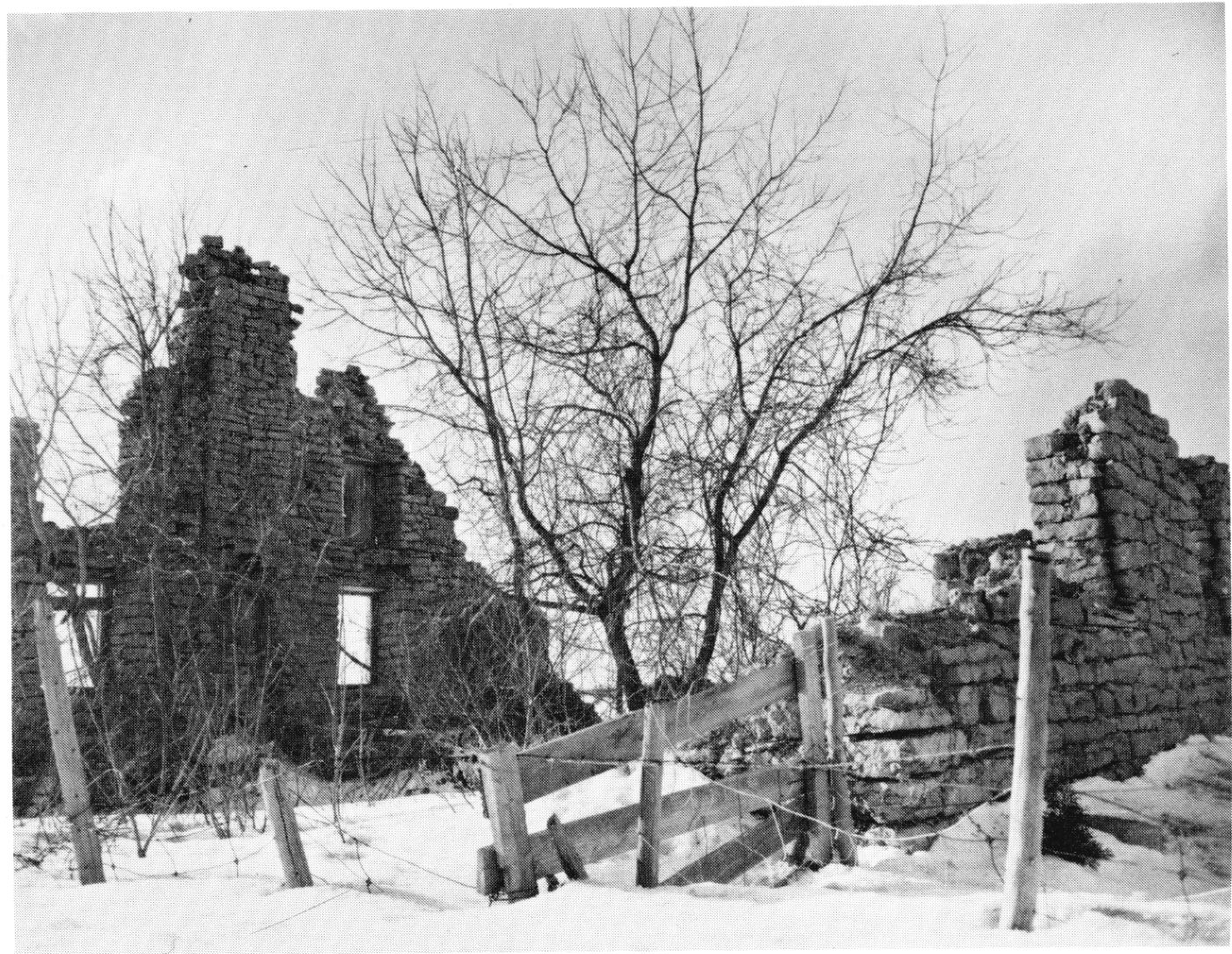 Photo en noir et blanc des ruines d'une maison en hiver.