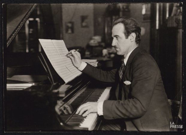 Photo en noir et bland de Rodolphe Mathieu assis au piano et composant une oeuvre. 