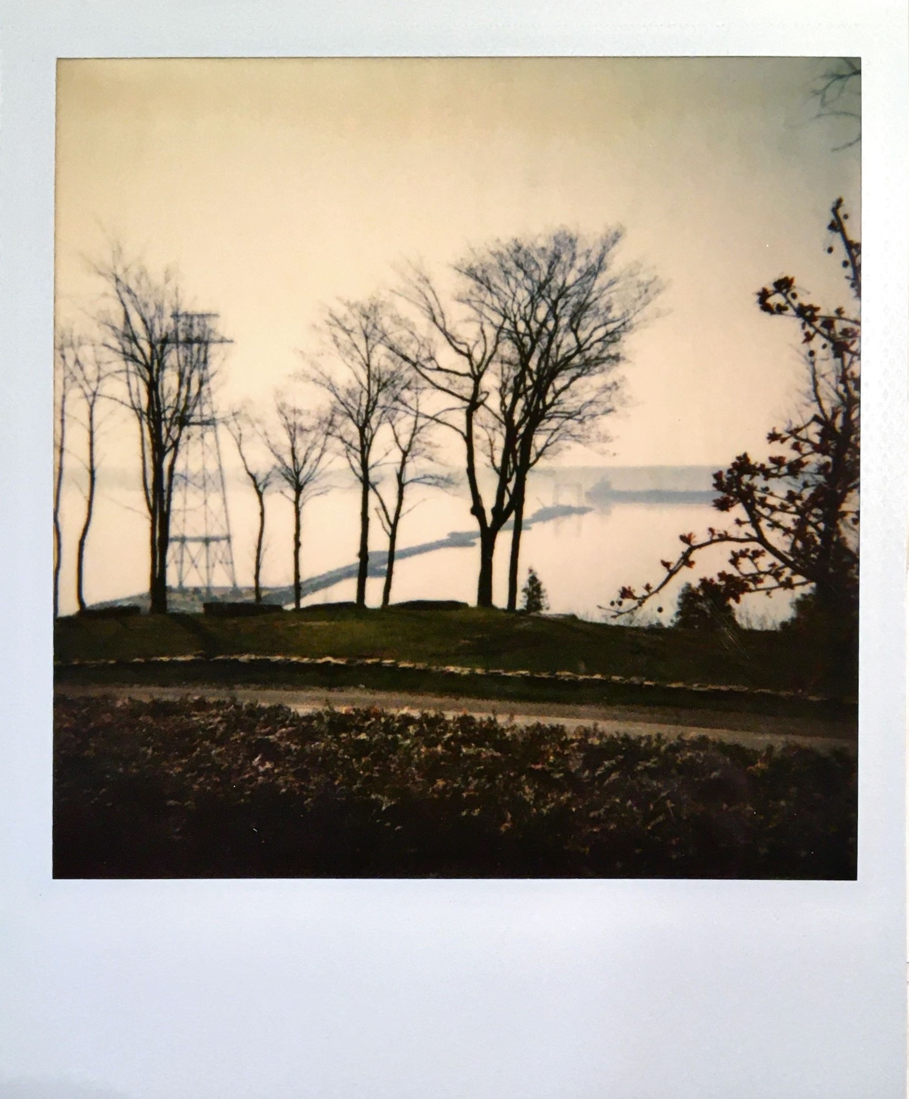 Photo de type « Polaroid » du fleuve. On y voit un premier pylône construit près de la berge et un chemin temporaire menant au milieu du fleuve.