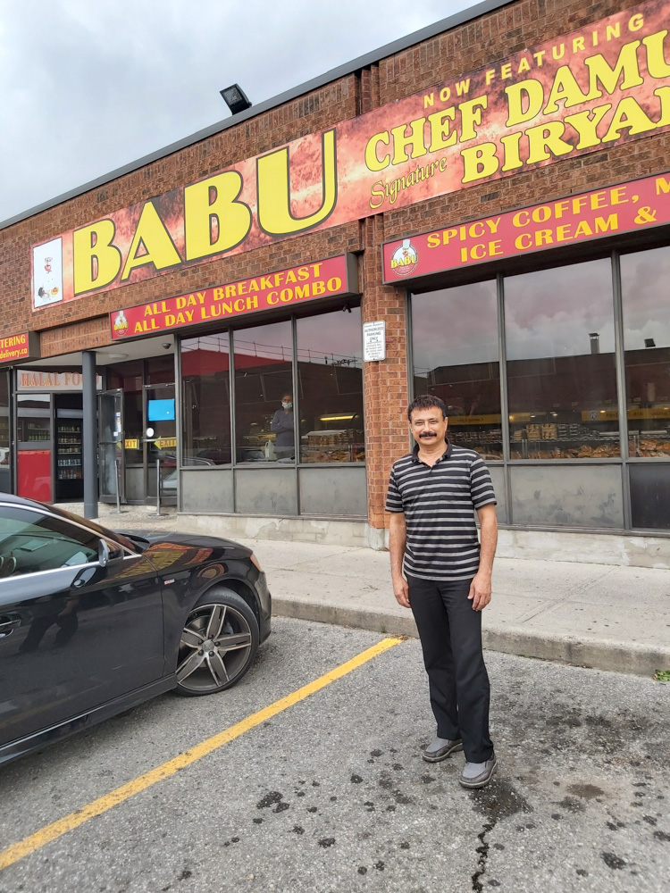 Un homme debout devant un restaurant appelé « BABU », qui propose des petits déjeuners et des déjeuners combos toute la journée et où l'on trouve désormais le biryani du chef Damu.