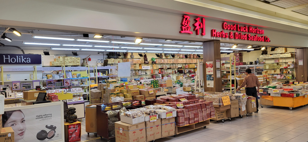 Un magasin très fréquenté à l'intérieur du centre commercial Agincourt Mall, avec des boîtes empilées contenant des herbes et des produits séchés.