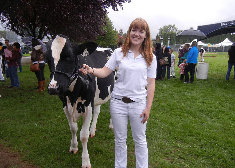 Photo en couleur d'une jeune femme qui mène une vache.