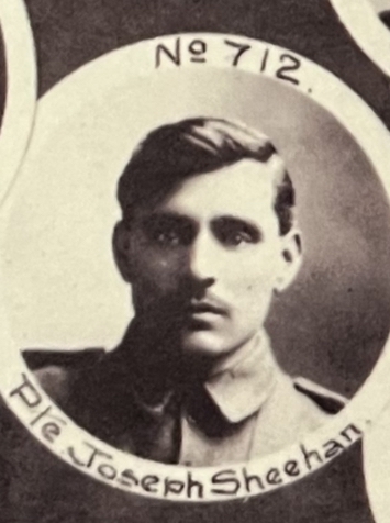 Portrait sépia d’un homme aux cheveux, moustaches et yeux foncés portant un uniforme militaire. La photo est de forme ronde et porte la mention No 712 Pte Joseph Sheehan inscrite autour du portrait. On voit d’autres photos circulaires partielles à l’arrière-plan sur un fond de papier noir.