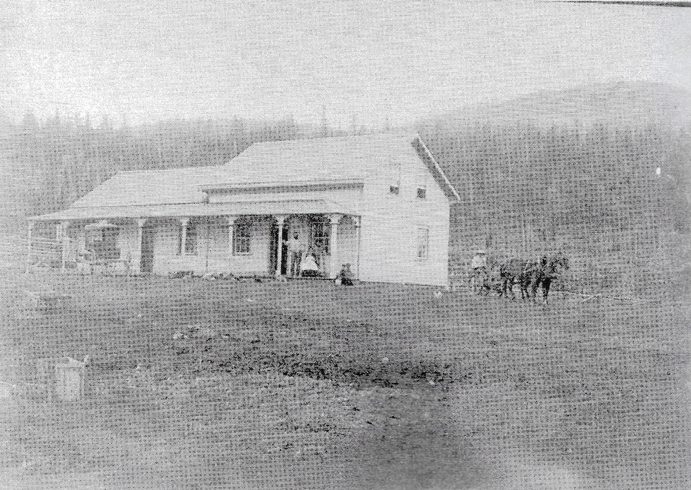 Maison en bois et charettes devant coline boisée