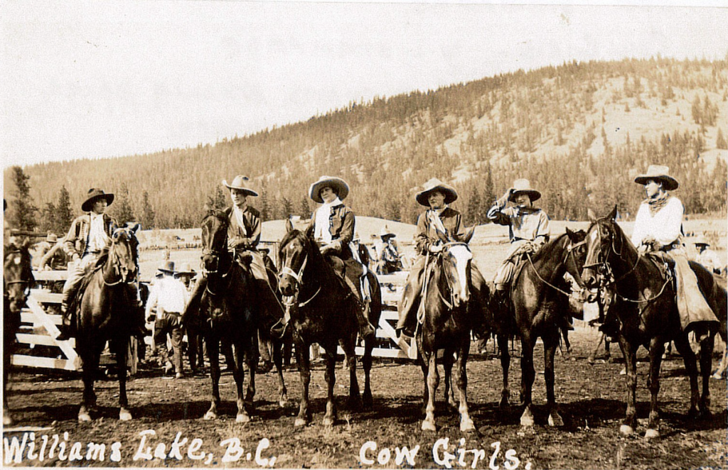 Six cowgirls on horseback with wooded mountain in background