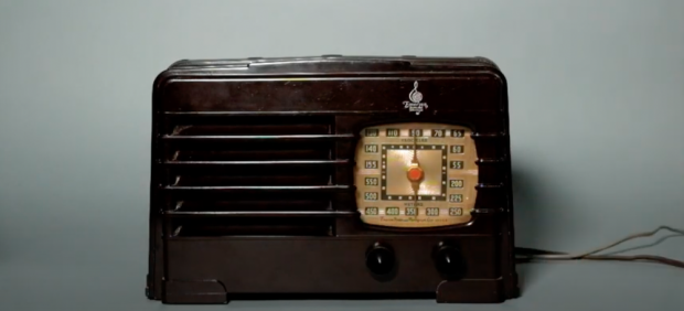Radio de table en plastique avec grille horizontale à gauche et cadran carré arrondi à droite. Deux interrupteurs sous le cadran.