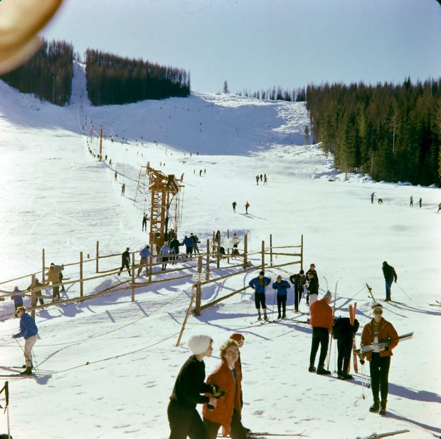 Photo colorée de skieurs en queue pour utiliser la remontée mécanique de ski. 