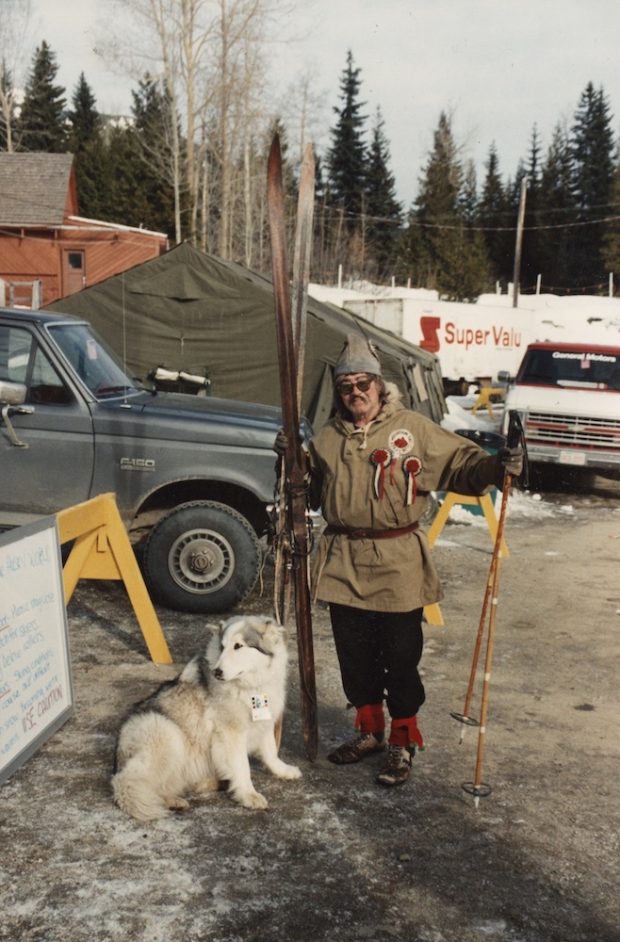 Photo couleur d’un homme vêtu comme Olaus Jeldness accompagné d’un chien sur un stationnement.