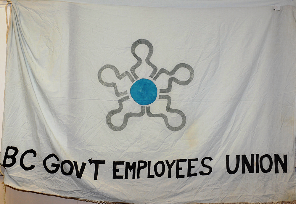 Photo d’un drapeau peint à la main lisant « BC Government Employees’ Union » et portant le logo du BCGEU.