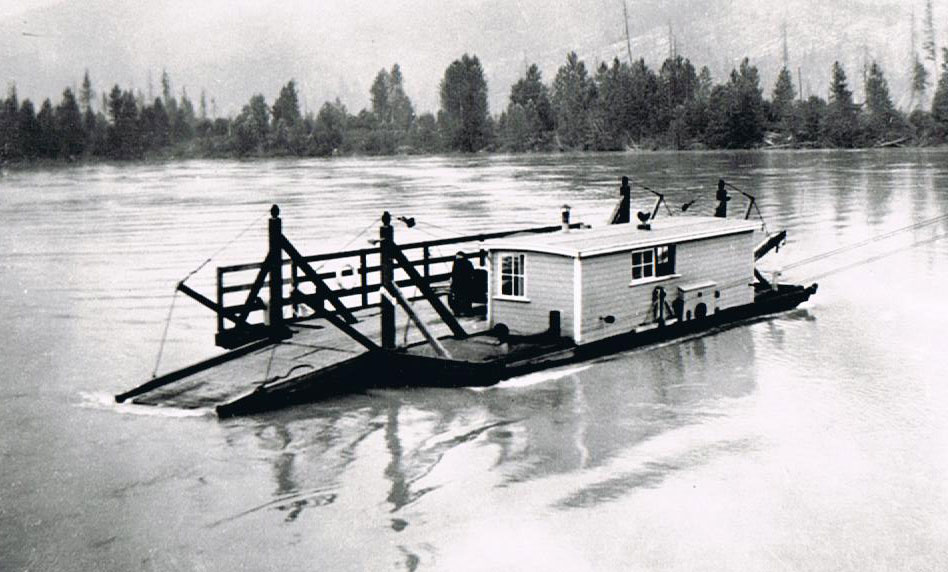 Photographie en noir et blanc d’un traversier qui traverse la rivière. Il y a des arbres en arrière-plan.