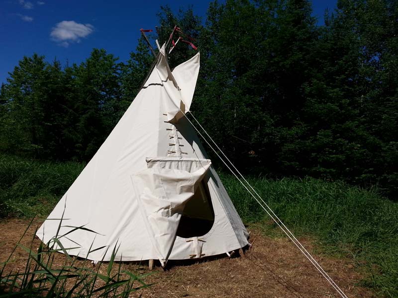 Photographie d'une tente tipi à l'extérieur.